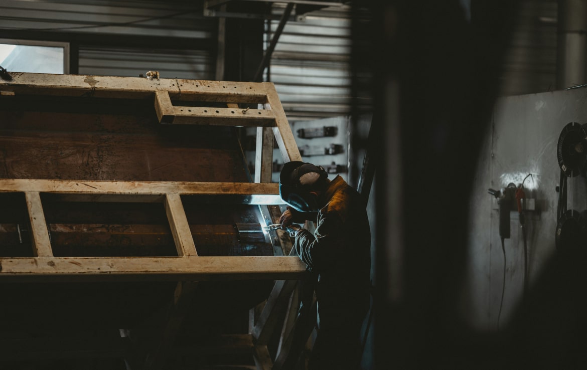 A person welding a large metal structure in a workshop